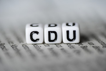 Word CDU formed by wood alphabet blocks on newspaper german party politics