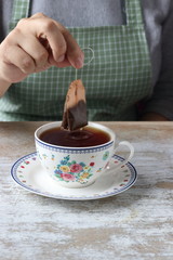 Dipping tea bag into a cup