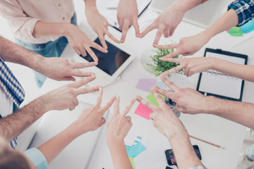 Cropped, top high angle view close up portrait of students hands showing putting v-signs in circle in workstation, harmony, motivation, inspiration, connection, achievement, organization concept