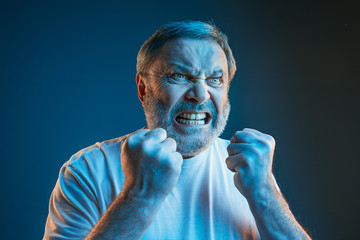 The senior emotional angry man screaming on blue studio background - obrazy, fototapety, plakaty