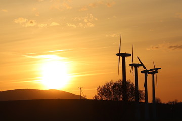 Wind power station in sunset. Romantic evening and modern technologies of ecologically clean electricity. Protection of the environment. Bright Future. An alternative way of extracting energy.