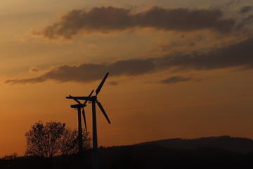 Obraz premium Wind power station in sunset. Romantic evening and modern technologies of ecologically clean electricity. Protection of the environment. Bright Future. An alternative way of extracting energy.