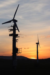 Obraz premium Wind power station in sunset. Romantic evening and modern technologies of ecologically clean electricity. Protection of the environment. Bright Future. An alternative way of extracting energy.