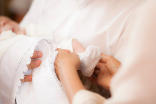 White sock on babys foot with mother hands taking care of child