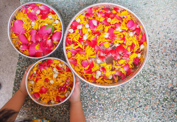 Calendula, Jasmine and roses in silver bowls, Young girl hold on silver bowl in Songkran festival at Thailand.
