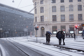 People Standing At Urban City Bus Stop While Snowing in Winter