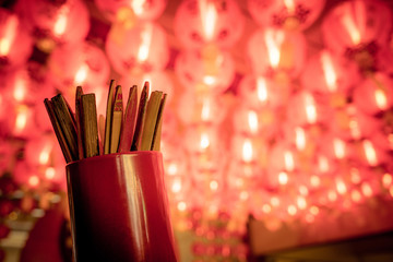 Close up of fortune sticks or Seam-Si or Chi-Chi sticks, shake for future fore with red Chinese paper lamp in the background. © wittayayut