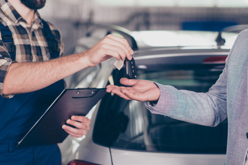 Close up cropped photo of professional smart experienced wearing uniform mechanic giving keys back...