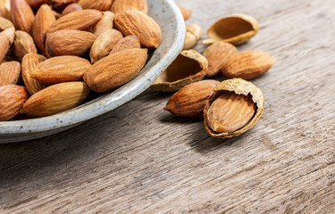 Roasted almonds, salt in dish of green on a wood table.