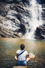 Fototapeta na wymiar Woman seat before beautiful waterfall in Sri Lanka.