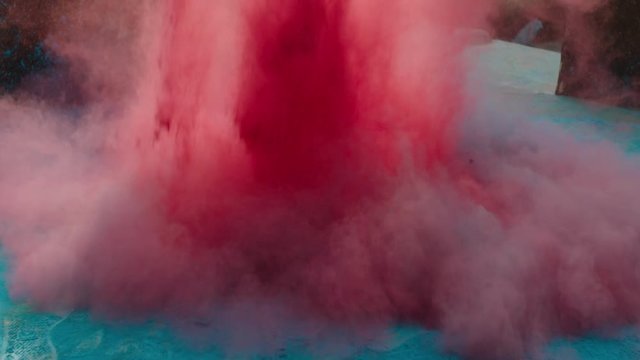 A slow motion video of red colored powdered dye used during the festival of Holi falling on the ground.