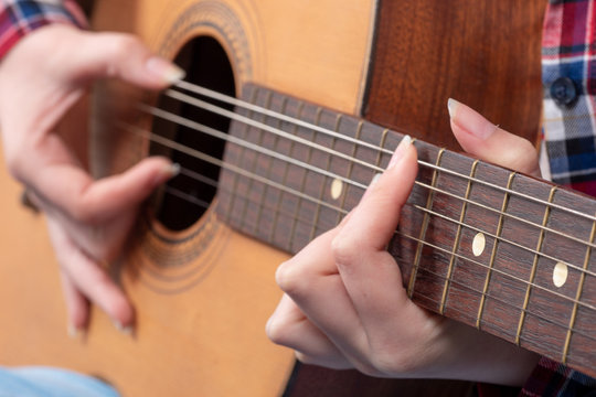 close-up of a young woman's hands playing guitar