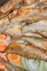 Fried fish smelt lies on the cut onion and carrot