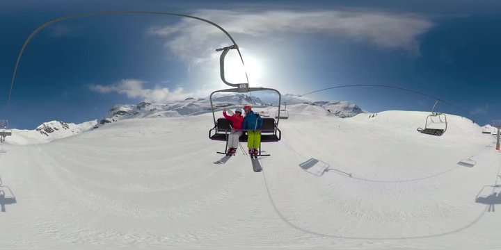360VR 4K man and woman going up with chair lift on sunny winter skiing day in mountains
