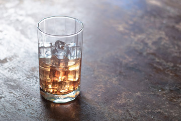 Glass of whiskey with ice on black background