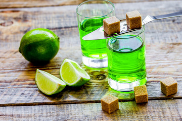absinthe with sugar cubes in spoon on wooden background