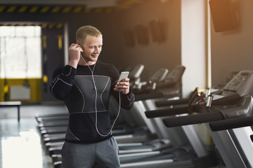 Young sporty man on treadmill in fitness club