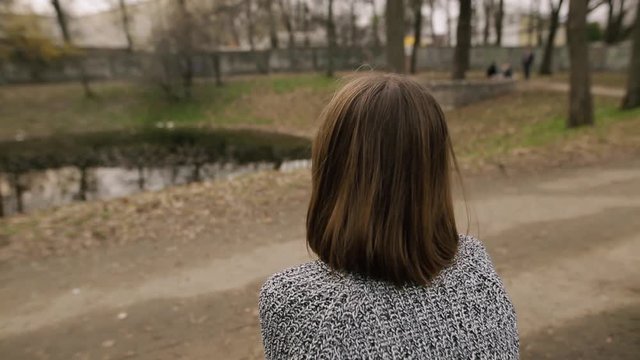 Woman removes scrunchie from her head, back view.