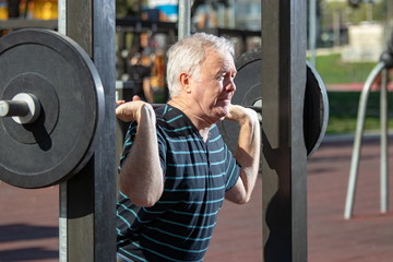 Elderly man lifting weights in Outdoors Gym