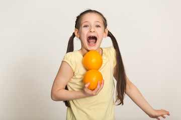 Fototapeta na wymiar Happy little girl having fun with oranges over white background