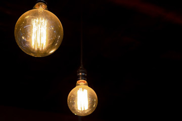 Vintage round tungsten filament bulb with dark background, technology and energy concept