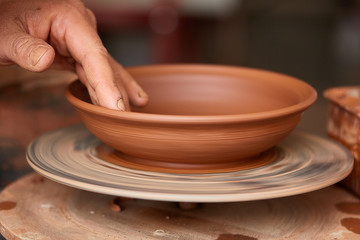 Making pottery on a potter's wheel in the workshop, close-up, selective focus.