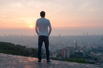 Chico mirando el skyline de la ciudad de Barcelona al amanecer