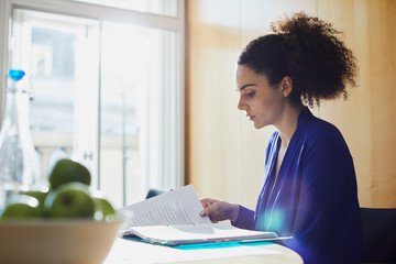 Young businesswoman reading paperwork at office desk