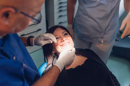 Dentist and dental nurse carrying out dental procedure on female patient
