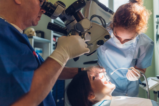 Dentist and dental nurse carrying out dental procedure on female patient