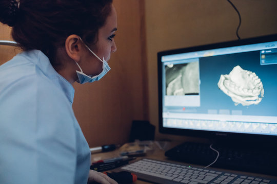 Female dentist looking at model of teeth on computer screen
