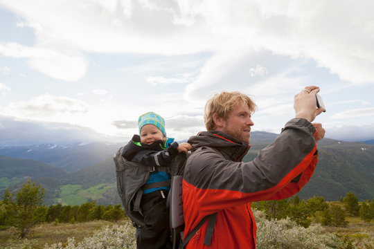 Male hiker with son photographing mountain landscape, Jotunheimen National Park, Lom, Oppland, Norway