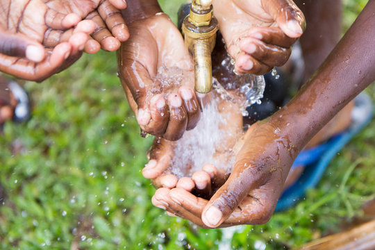 Ugandan children washing their hands at an outdoor water tap
