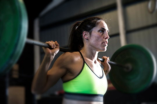 Woman exercising in gym, using barbell