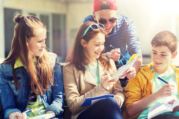 education, high school and people concept - group of happy teenage students with notebooks learning at campus yard
