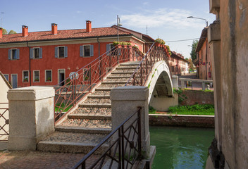 canal crossed by a cobblestone bridge, to move the houses of the village in the province of Milan, Italy