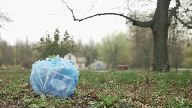 Close-up of garbage in the park, jogging girl in black suit in the background blurred, plogging concept, 50 fps