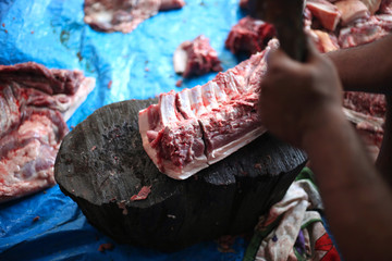 Butcher cut raw meat of a pig with a knife at table in the slaughterhouse