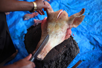 Butcher cut raw meat of a pig with a knife at table in the slaughterhouse