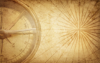 Old vintage retro compass on ancient map. Survival, exploration and nautical theme grunge background