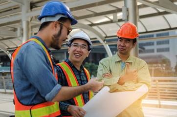 group of engineer, technician and architect with safety helmet planning about building plan with blueprint in modern city building background, construction site, business, industry and worker concept