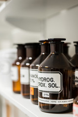 Close-up of the labeled glass container of a chemical pharmaceutical substance on a shelf, next to...