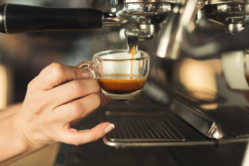 Closeup of barmen hand brewing espresso in professional coffee machine