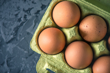 Fresh farm eggs in green tray, on beautiful dark background. Home eco-friendly products