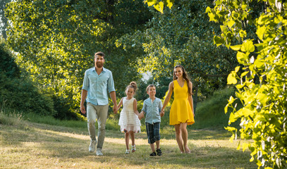 Full length view of a happy family with two children wearing casual summer clothes while holding...
