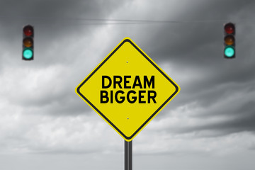 Dream Bigger inspirational street sign with green traffic light