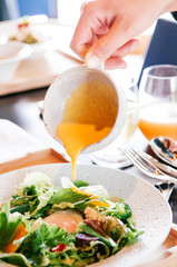 Pouring cream vinaigrette dressing on mix salad dish