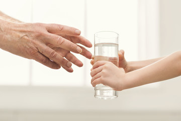 Kid giving glass of water to mgrandfather