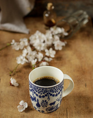 coffee in a white cup on the table and flowering spring twigs