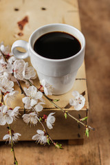 coffee in a white cup on the table and flowering spring twigs
